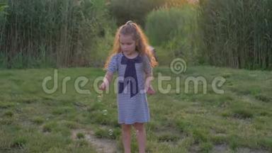 可爱的小女孩吹着泡泡，在草地上玩耍